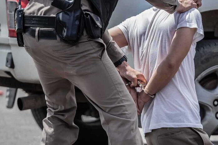 1705187374 featured image Police officer handcuffing person against vehicle wheel