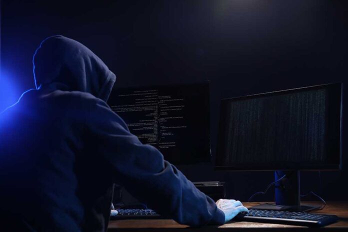 1708895812 featured image Hooded figure using dual monitors in dark room