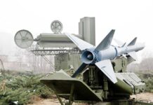 Military missile launcher with radar systems in a foggy field.