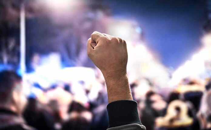 1227767950 featured image protest Raised fist in a crowd at night