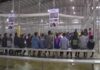 illegal immigrants are sitting on benches inside a fenced facility