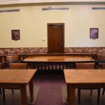 Empty courtroom with wooden tables chairs and a door