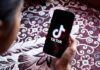 Hand holding phone showing TikTok logo