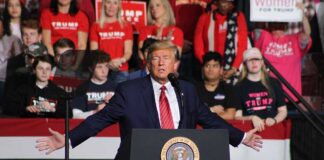 Person speaking at podium with crowd behind them
