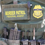 Vegan Cult MURDERS Border Agent — DEATH PENALTY Border Patrol vest with gear and communication equipment.
