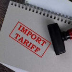 Trump’s Tariff Bombshell Shakes Furniture Industry Notebook with Import Tariff stamp and rubber stamper.