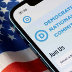 DNC Speaker Dismisses Crime Concerns Phone displaying Democratic National Committee website over flag.
