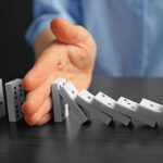 Postal Confusion Grips Europe — Shipments Blocked Hand stopping falling row of dominoes.