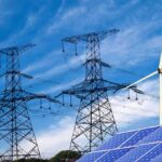 Solar panels and a wind turbine with power lines against a blue sky
