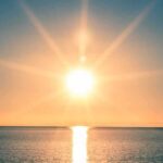 A serene sunrise over a calm ocean with vibrant colors in the sky