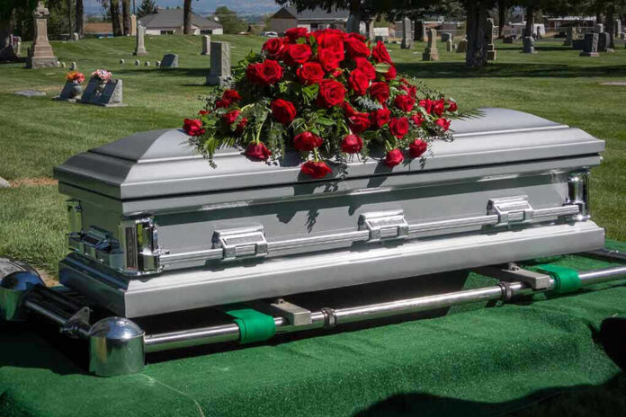 Silver casket with rose bouquet in a cemetery.