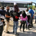 Families and children waiting in line near a bus