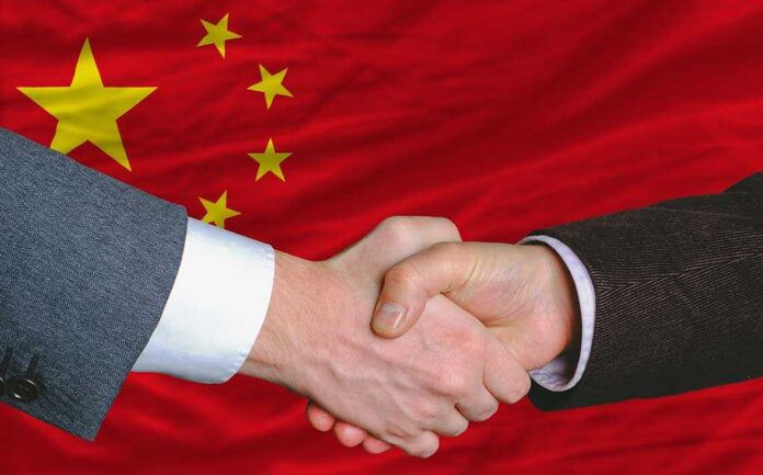Two hands shaking in front of the Chinese flag