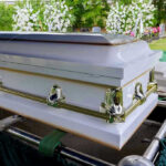Couple of 70-Years DIE Holding Hands After Tragic Accident White coffin with flowers in the background.