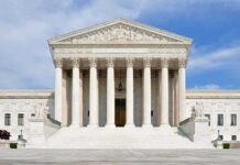 Front view of the Supreme Court building with large columns and steps under a blue sky