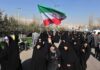 Iran’s Shadow Army Stages Coup – Tehran Scrambling! Group of women in black attire marching with an Iranian flag