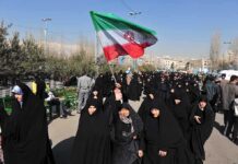 Iran’s Shadow Army Stages Coup – Tehran Scrambling! Group of women in black attire marching with an Iranian flag