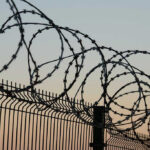 Barbed wire fence against sunset sky background.