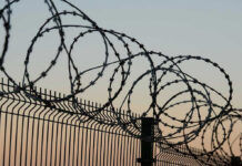 Barbed wire fence against sunset sky background.