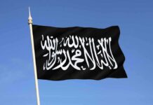 Black flag featuring Arabic script against a blue sky