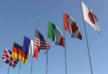 France Implements Immigration FREEZE! Flags of seven countries against clear blue sky.