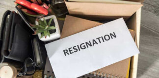 Envelope labeled RESIGNATION atop office supplies in box.