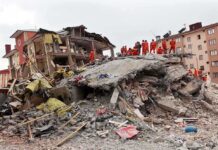 Shocking School Dorm Attack – Teens Caught in Wartime Crossfire Rescue workers in orange uniforms on a collapsed building site after an earthquake