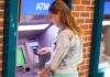 Trump’s Order Sparks PERSONAL Banking Chaos Young woman using an ATM in an urban environment