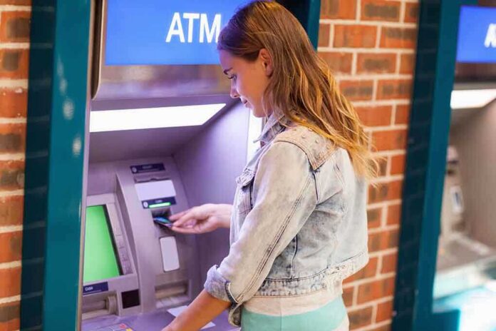 shutterstock_160498727 Young woman using an ATM in an urban environment