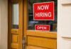 A door with a 'Now Hiring' sign and an 'Open' sign