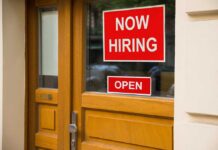 A door with a 'Now Hiring' sign and an 'Open' sign