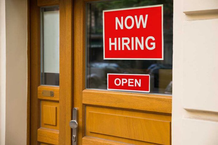 shutterstock_323338607 A door with a 'Now Hiring' sign and an 'Open' sign