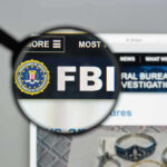FBI Catches MOST WANTED Fraudster! FBI website shown through magnifying glass.
