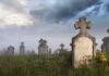 Foggy graveyard with tombstones and crosses under a cloudy sky