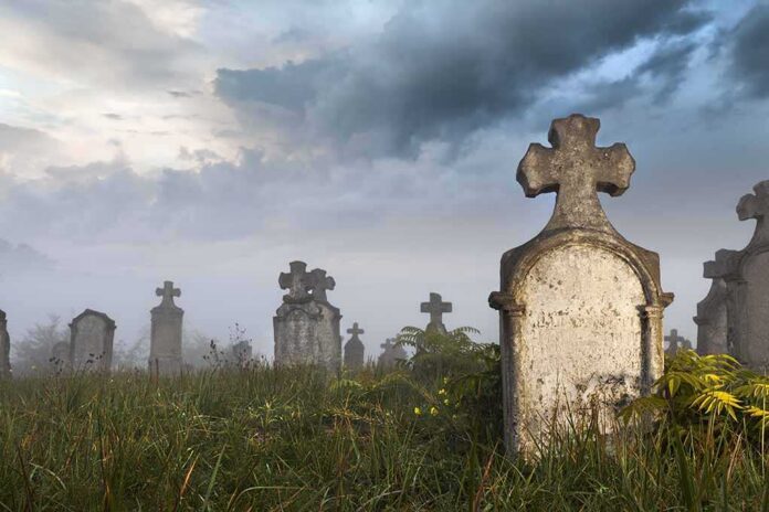 Foggy graveyard with tombstones and crosses under a cloudy sky