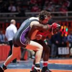 Two wrestlers competing on a mat during a match