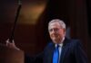 Missing Senators Wife SPOTTED – Fuels Mystery A political figure smiling while holding a microphone