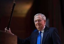 Missing Senators Wife SPOTTED – Fuels Mystery A political figure smiling while holding a microphone