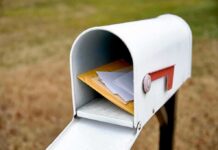 Suspect ARRESTED For Stealing Ballots Out of Mailboxes White mailbox with red flag holding envelopes and padded mailers