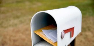White mailbox with red flag holding envelopes and padded mailers