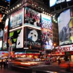 Vibrant night scene of Times Square filled with theater advertisements and neon lights