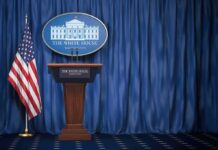 Liberal Media Get Trump Back After Ban White House press briefing podium with U.S. flag and blue curtain