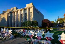 Synagogue exterior with memorial flowers and star-shaped tributes on lawn
