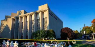 Synagogue exterior with memorial flowers and star-shaped tributes on lawn
