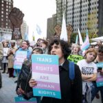 Crowd of protesters holding trans rights signs at a city rally