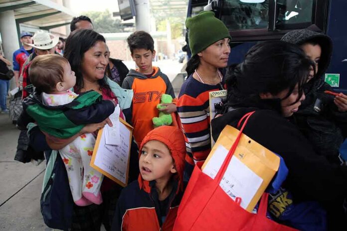 Group of people with children waiting in line near a bus