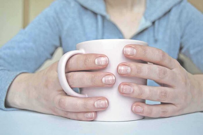 shutterstock_1395119669 Hands holding a light pink mug