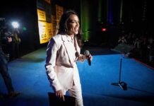 Woman in a light suit holding a microphone on stage