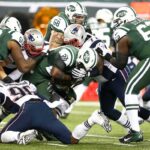 Football players collide in a heavy tackle at the line of scrimmage