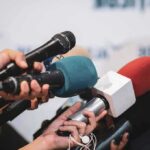 Cluster of microphones held toward a speaker at a press event